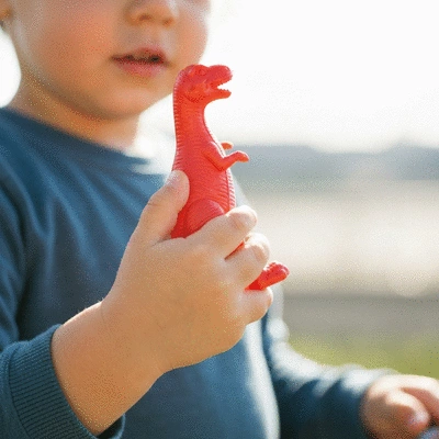 Close-up of a child's hand touching a wooden rocking horse made from recycled materials, soft focus background